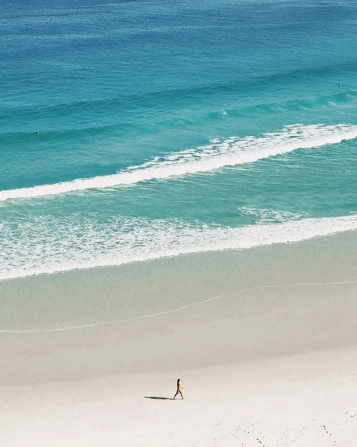 Beautiful sunny beach scene with ocean waves and pristine white sand representing optimal sun exposure for vitamin D synthesis and healthy outdoor lifestyle